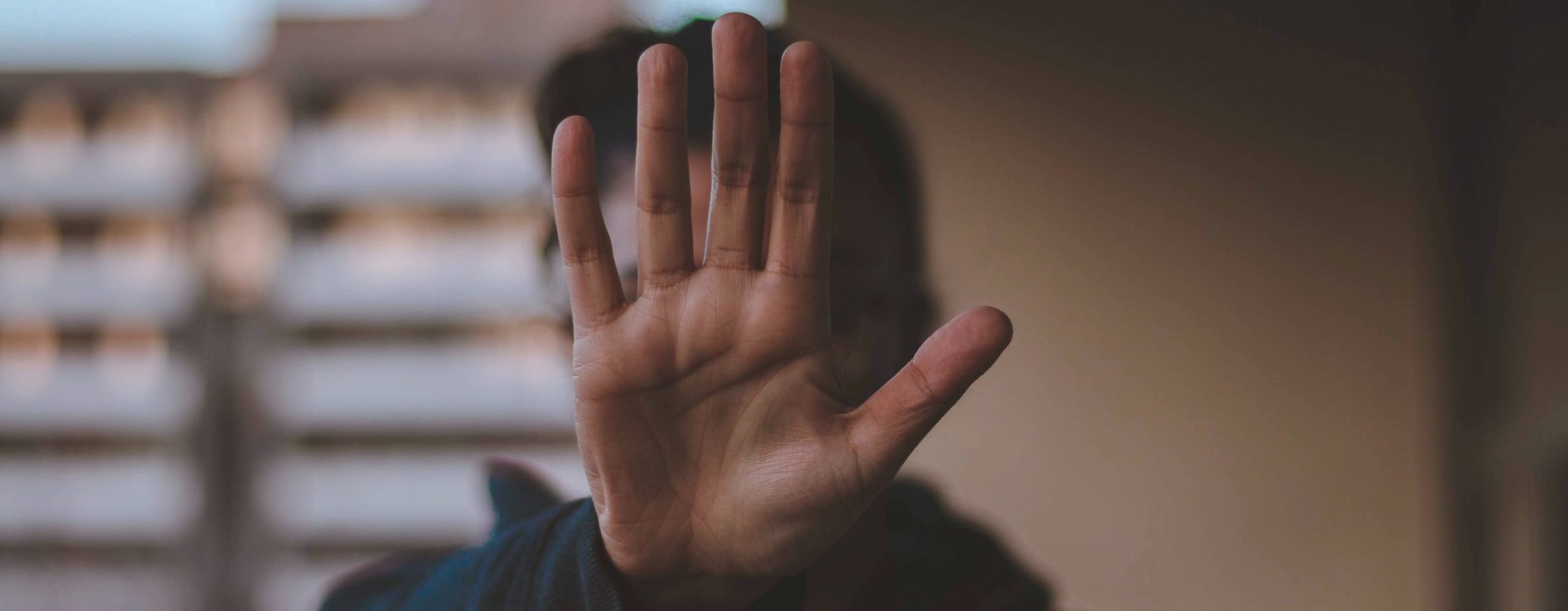 woman holding hand in front of her face as a sign to stop